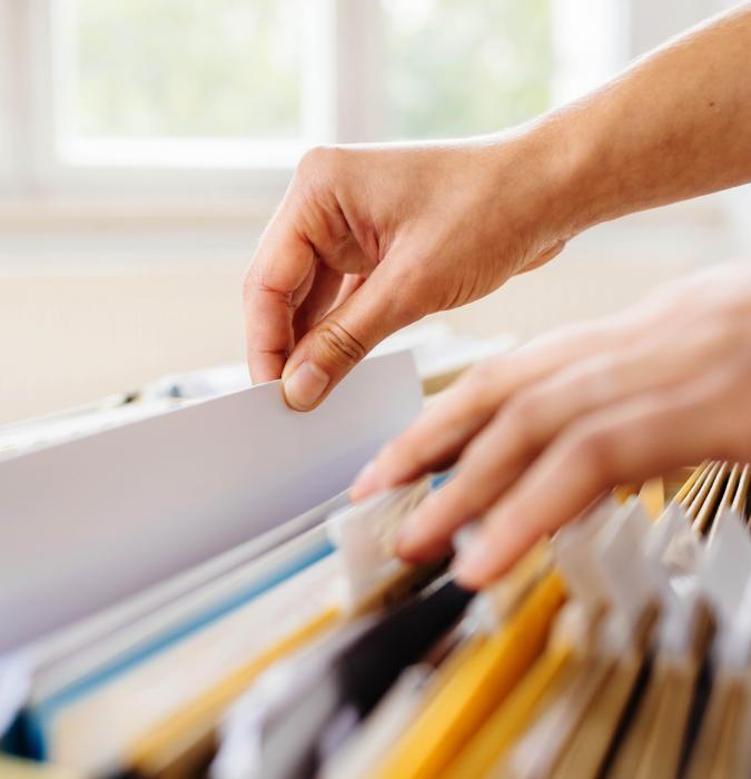 A woman sorts file folders for students. 