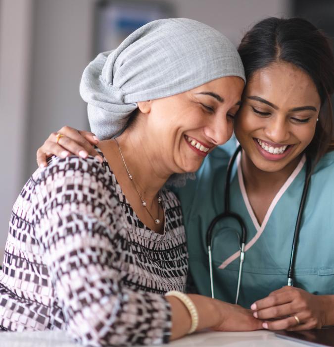 A provider comforting a cancer patient in her hospital room. 